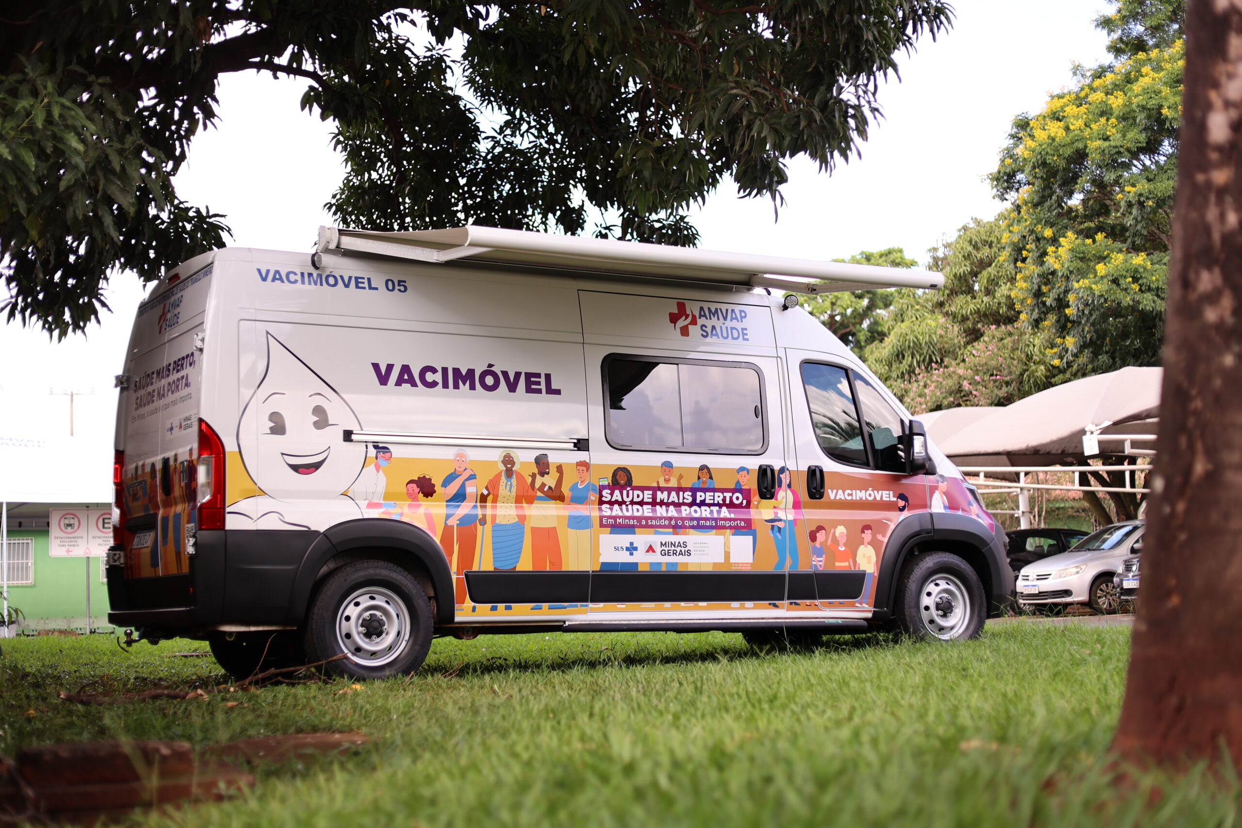 Veículo van do Vacimóvel estacionado em um gramado com tenda aberta